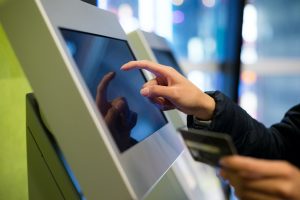 Woman using credit card on automatic ticketing machine